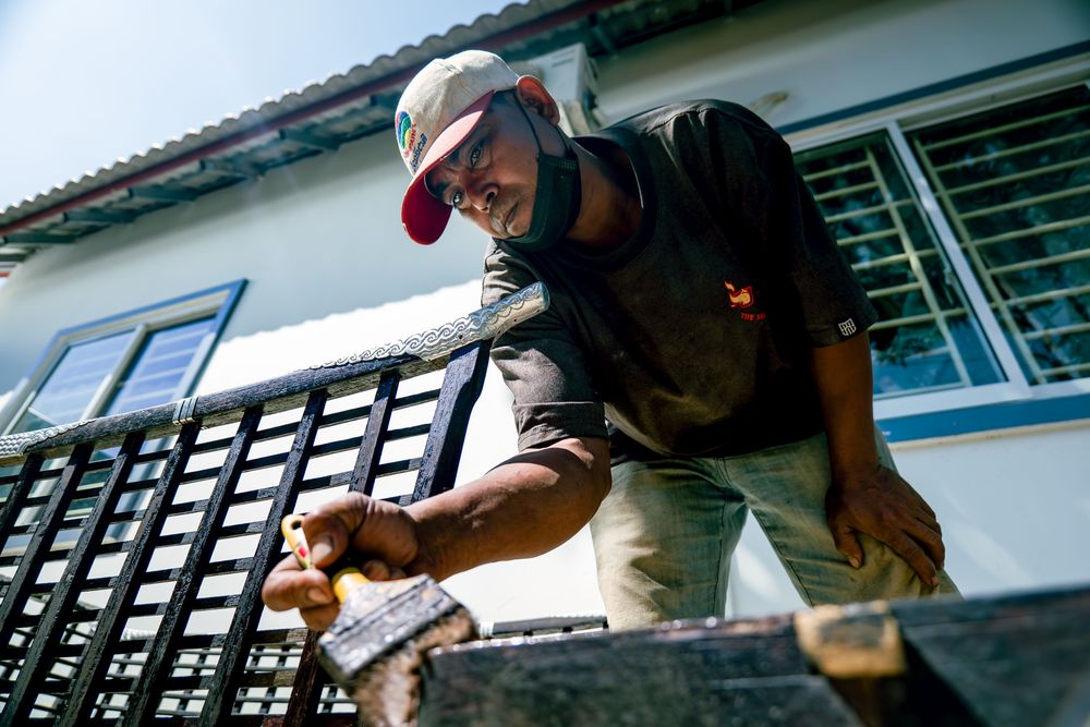 Peintre travaillant au pinceau sur une rambarde extérieure
