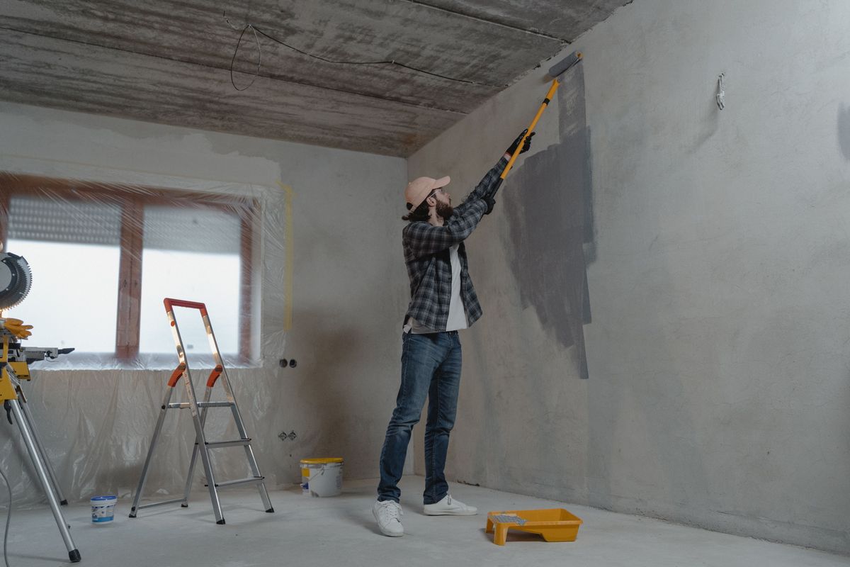 Peintre passant le rouleau au plafond d'une pièce à rénover