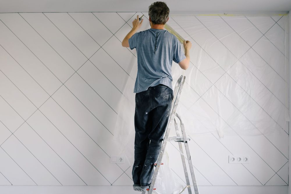 Homme sur un escabeau posant un papier peint à motifs